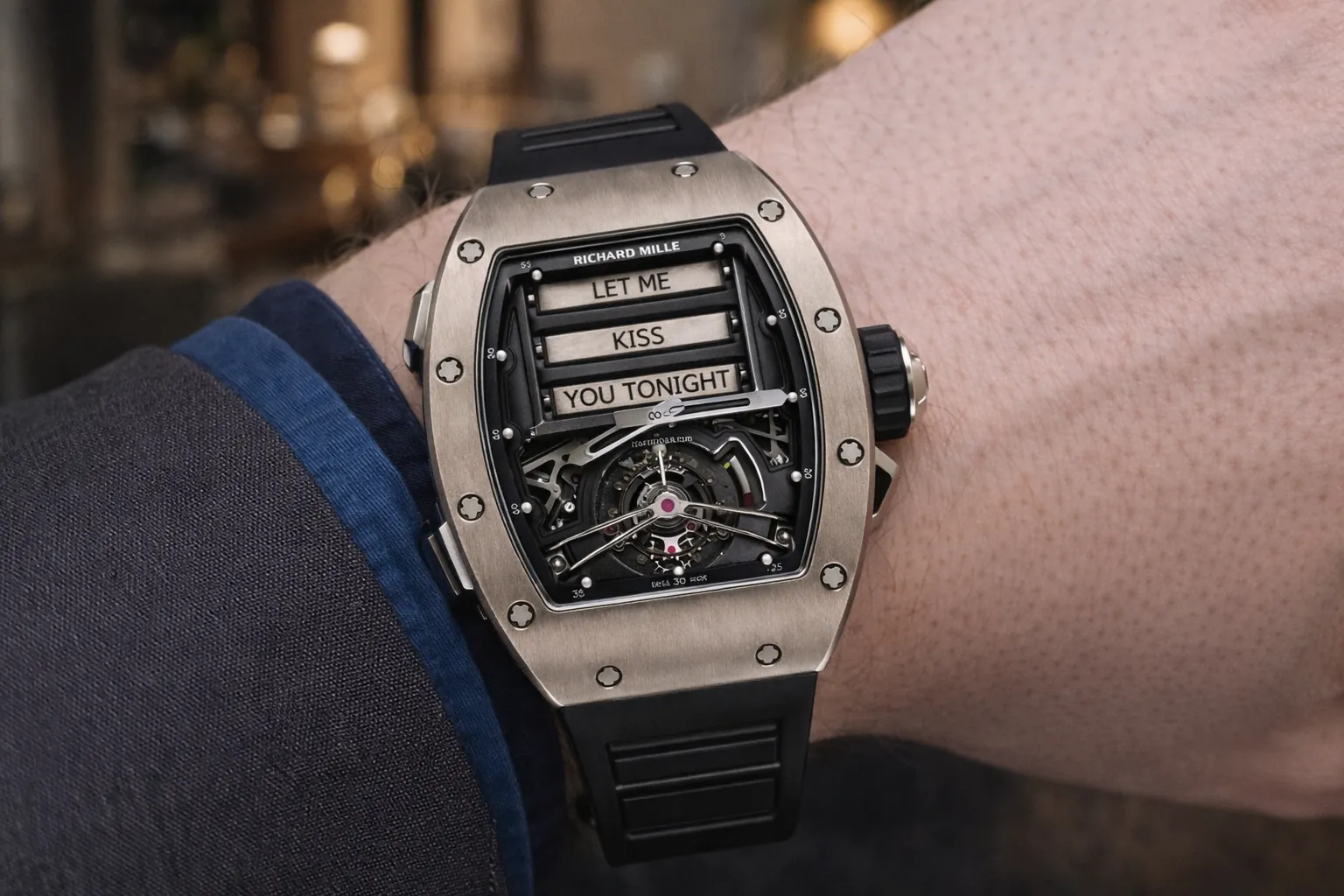 Iconic on-wrist shot of the Richard Mille RM 069 replica, the legendary "Let Me Kiss You Tonight" timepiece. Featuring a brushed titanium tonneau case, a playful message dial with iconic romantic text, and a fully visible skeletonized tourbillon movement, paired with a sporty black rubber strap. This premium super clone delivers the iconic RM bold design and haute horlogerie craftsmanship for collectors.