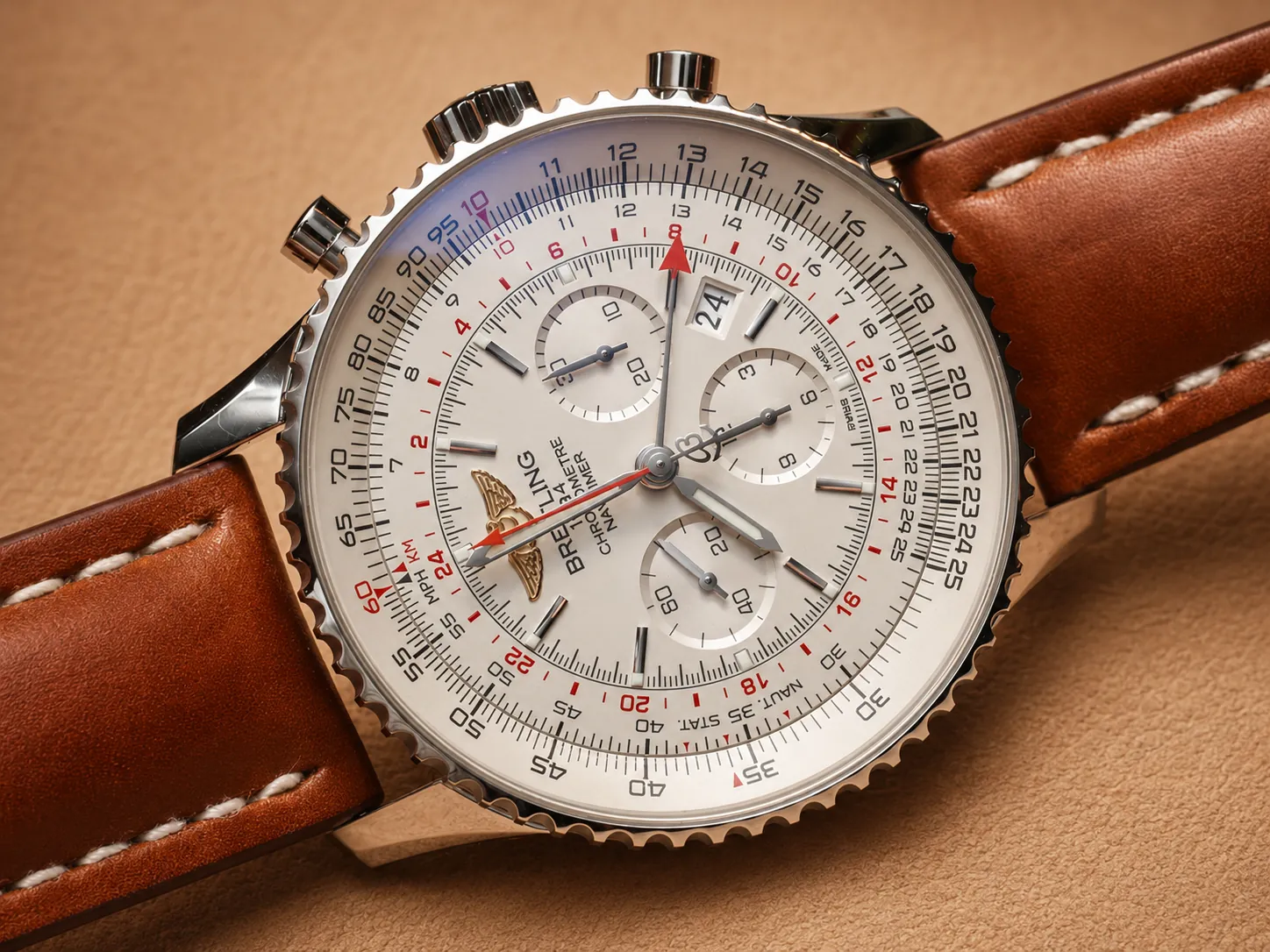 Detailed close-up of classic Breitling Navitimer replica with vintage brown leather strap, showcasing the iconic slide rule chronograph dial. This breakdown covers the two core slide rule components for flight calculations: the stationary fixed inner dial scale marked with red "10" index and STAT/KM/NAUT unit tags, plus the rotatable ridged outer bezel scale. Both logarithmic scales use flexible digit values without printed decimals, where each number can represent 10x scaled figures to handle multiplication, division and aviation unit conversions.